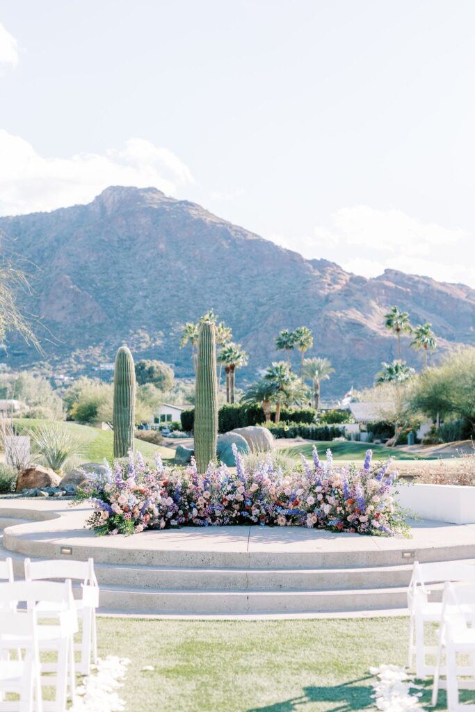 Rounded ground floral arc in raised outdoor ceremony altar space at Mountain Shadows.