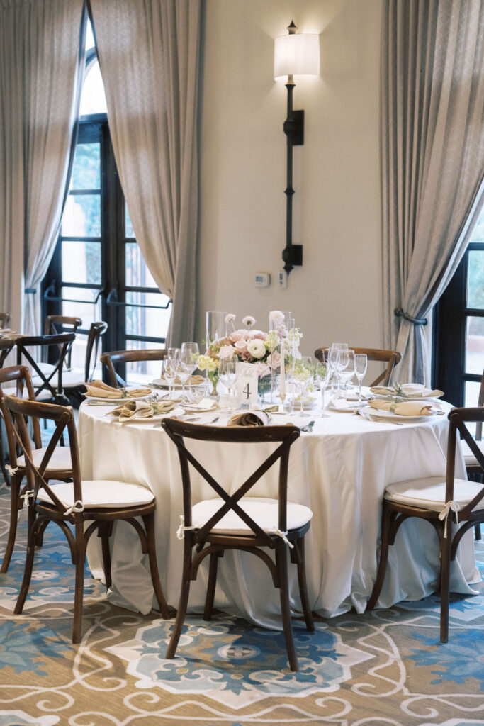 Round wedding reception table with floral centerpiece in center with white linens.