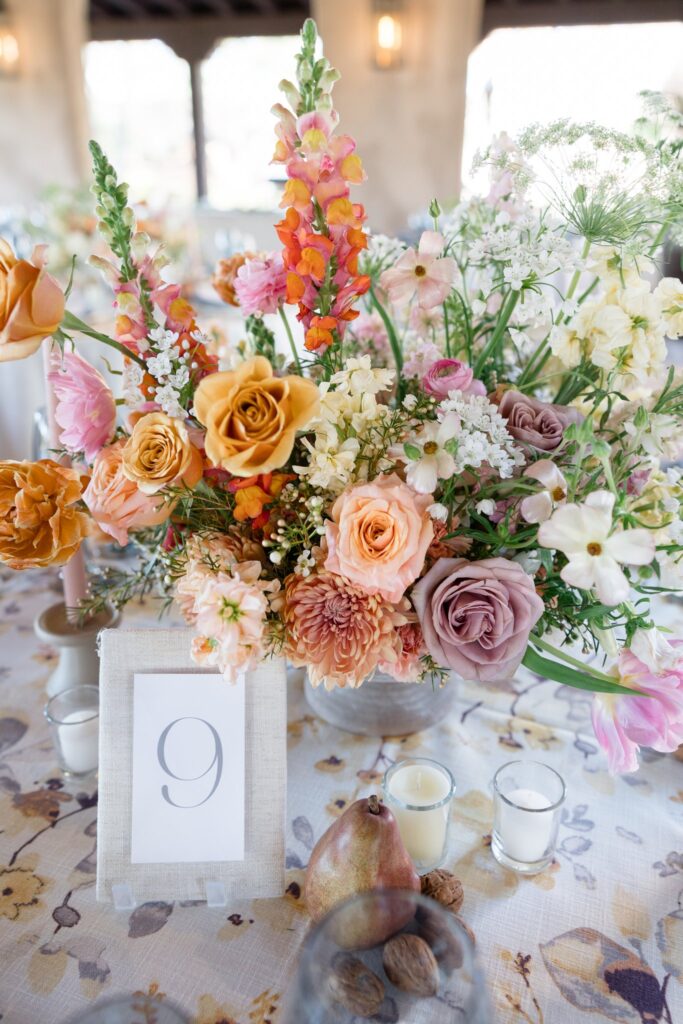 Wedding reception centerpiece of white, pink, gold, peach, and mauve flowers.