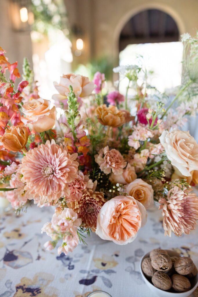 Wedding flowers in gold, pink, and peach colors in reception centerpiece.