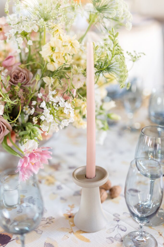 Pink taper candle in stone colored candle holder on wedding reception table.