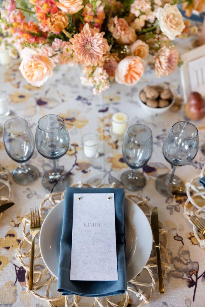 Wedding reception place setting and centerpiece of white, pink, gold, peach, and mauve flowers.