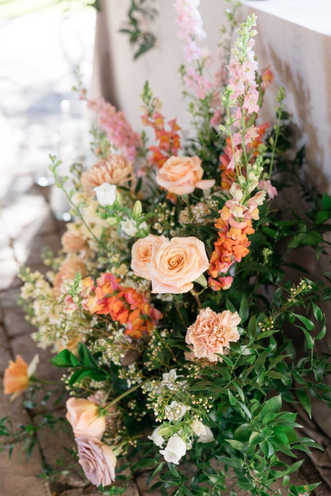 Ground floral of pink, peach, and white flowers at wedding.