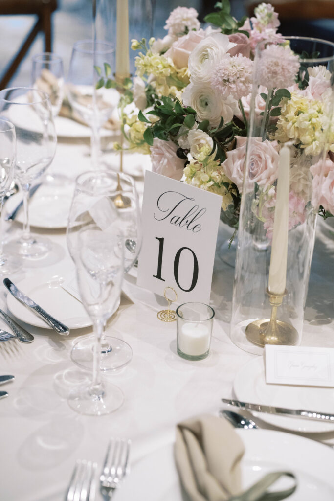 Wedding reception table with pink, white, cream, and mauve colored flowers centerpiece.