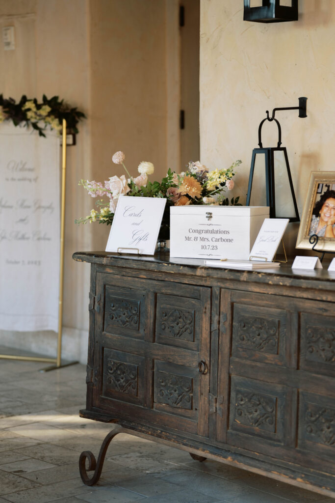 Gift table for wedding with floral arrangement in back corner.