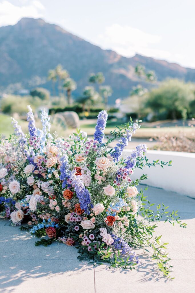 Rounded ground floral arc in raised outdoor ceremony altar space at Mountain Shadows.