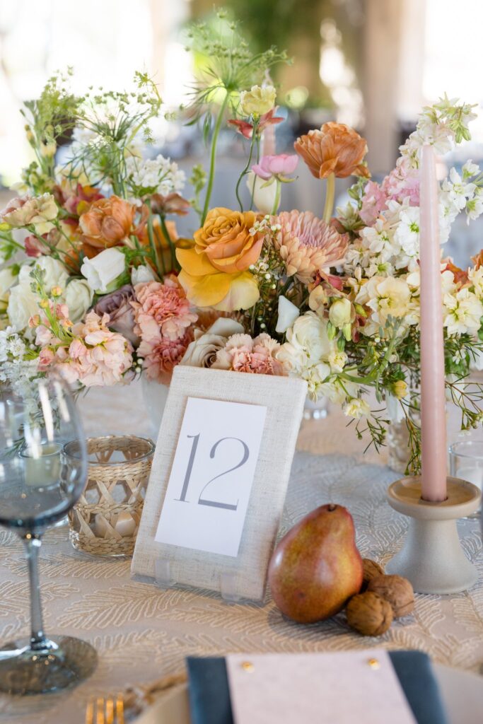 Wedding reception centerpiece of white, pink, gold, peach, and mauve flowers.