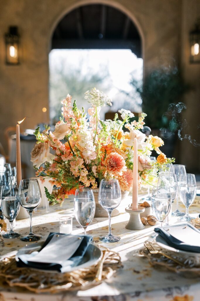 Wedding reception centerpiece of white, pink, gold, peach, and mauve flowers.