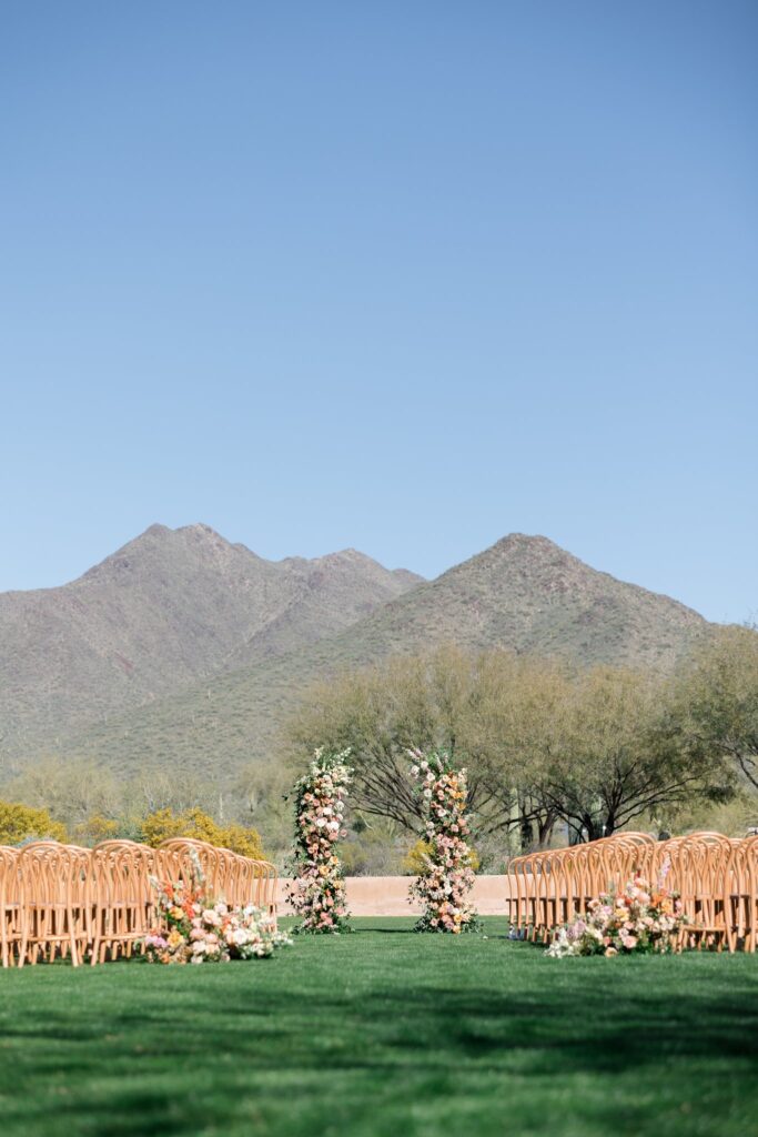 Outdoor wedding ceremony at Windgate Ranch with ground back of aisle flowers and two floral pillars in alar space.