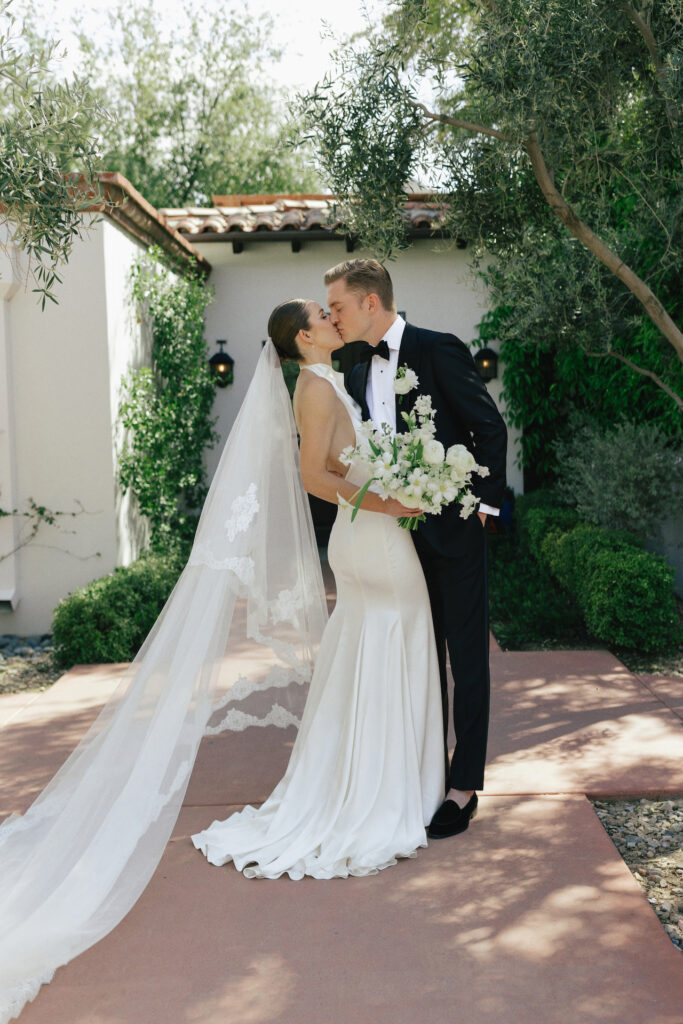 Bride and groom kissing outside on sidewalk at El Chorro.