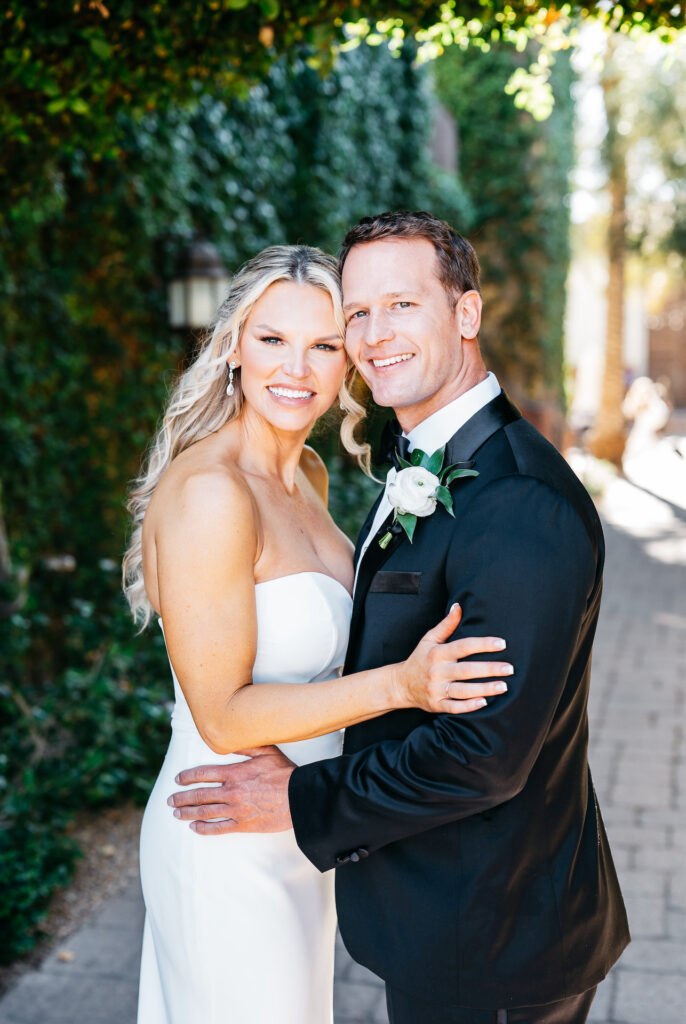 Bride and groom embracing, leaning heads together smiling at camera.