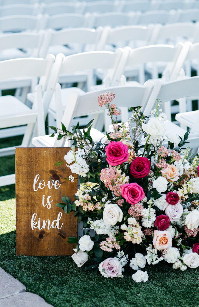 Wedding ceremony back of aisle ground floral arrangement of pink shades and white flowers.