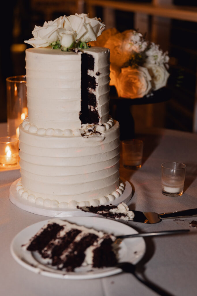 Two tier white frosting wedding cake with roses added to top.