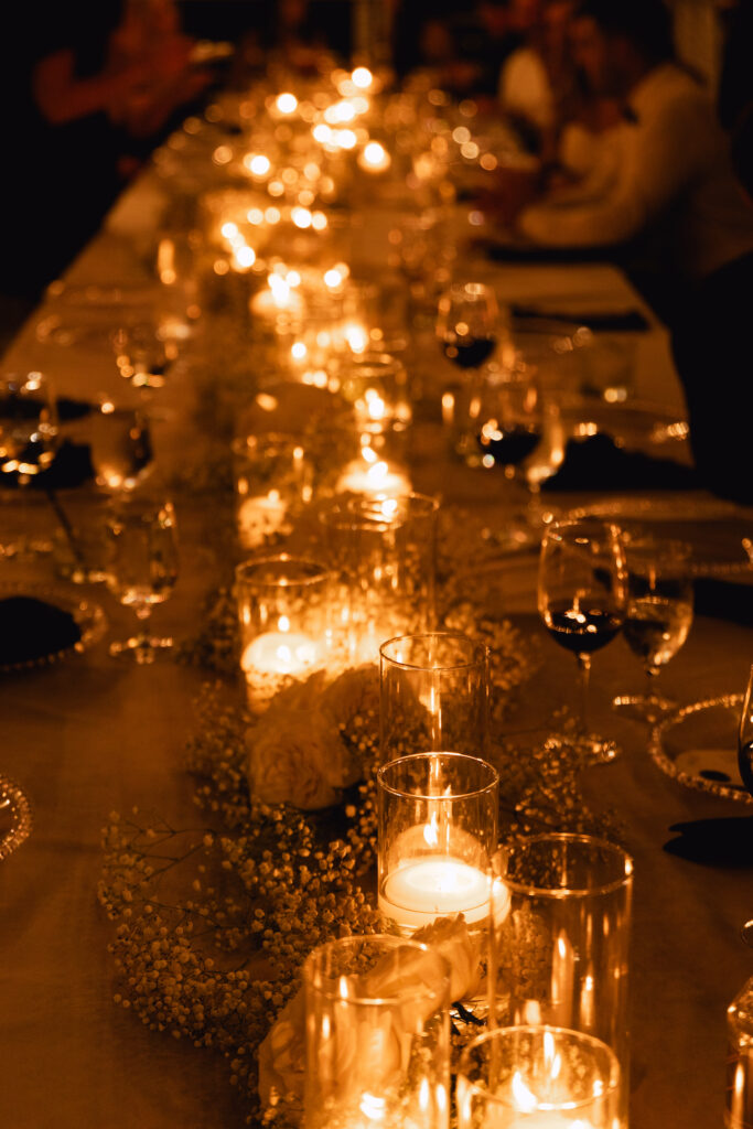 Evening candlelit long reception table with floating candles and babies breath down center.