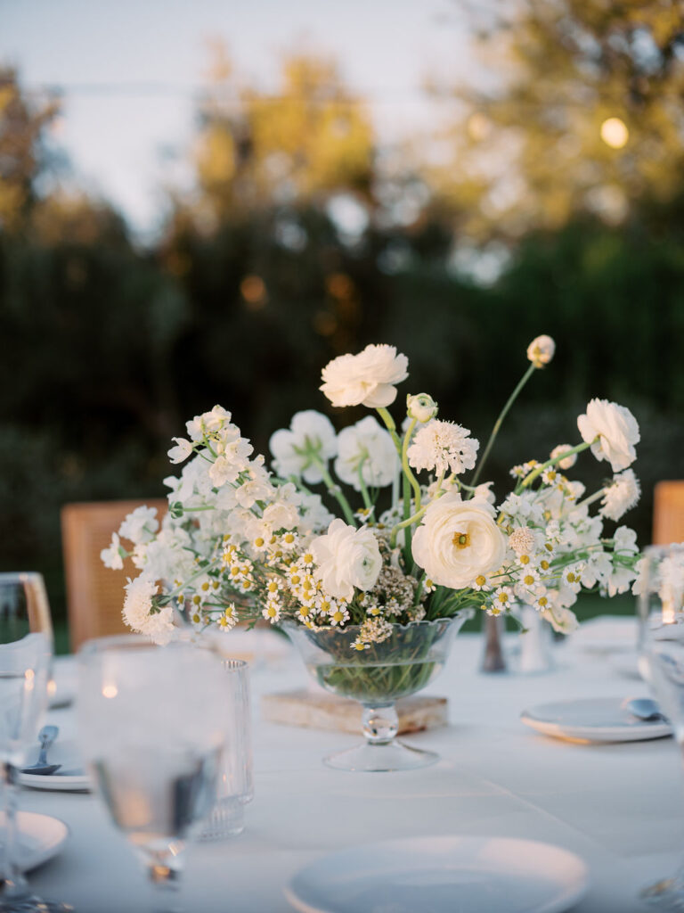 Garden style wedding reception centerpiece of white flowers including chamomile and ranunculus.