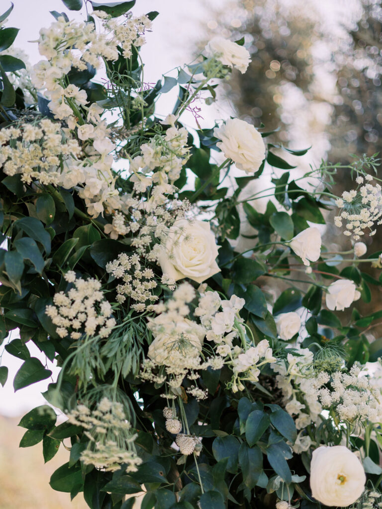 Close up image of wedding ceremony arch of white flowers and greenery.