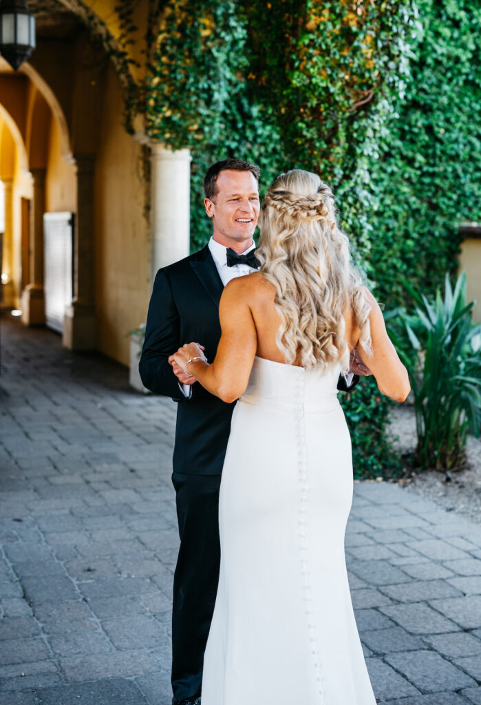 Groom seeing bride, holding her hands and smiling.