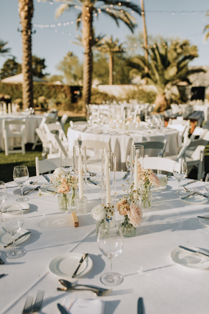 Wedding reception round table centerpiece of bud vases of white and blush flowers and pillar candles of white.