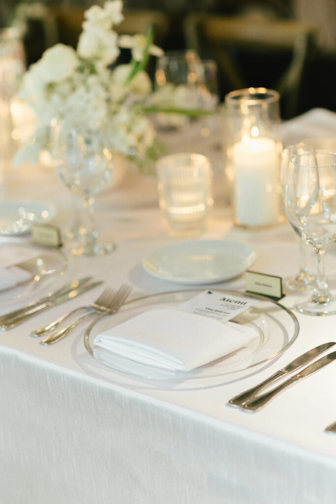 Wedding reception place setting table with candles and flowers.