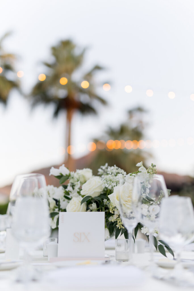 Reception table centerpiece with white flowers and greenery.