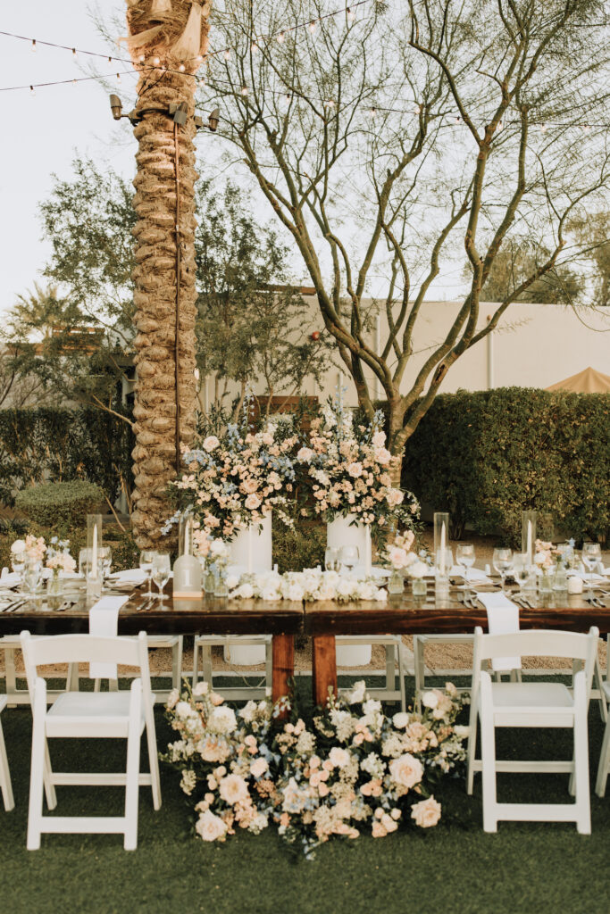 Andaz resort outdoor wedding reception head table floral decor on ground and pillars behind.