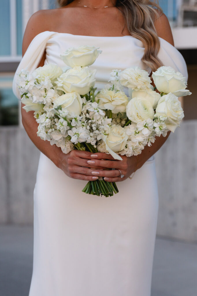 White wedding flowers bouquet held by bride of roses and snapdragons.