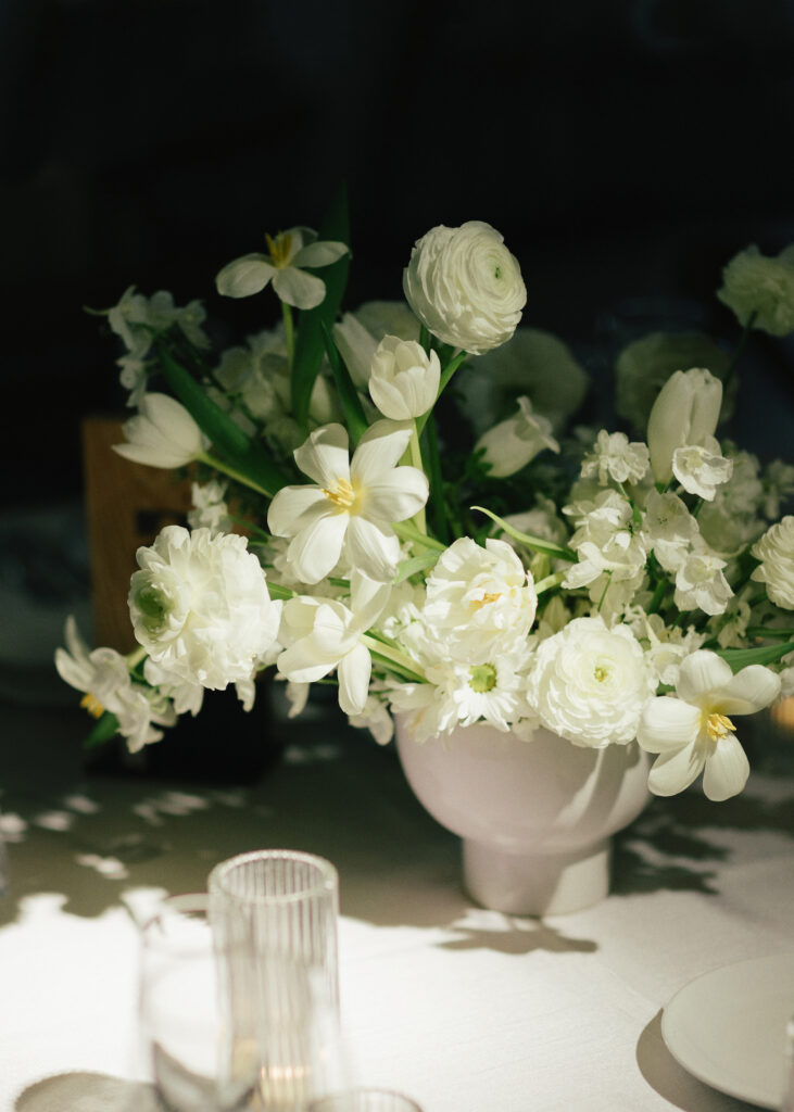 Wedding reception floral centerpiece of white flowers and minimal greenery.