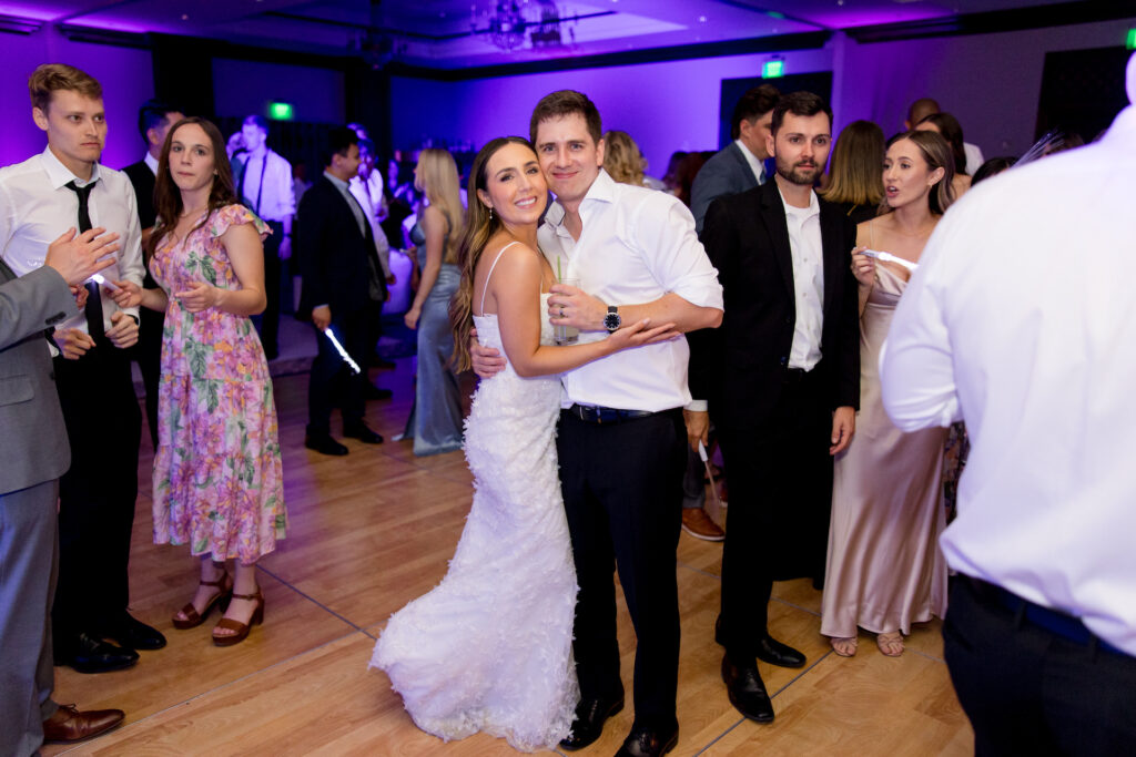 Bride and groom on dance floor during wedding reception, embracing.