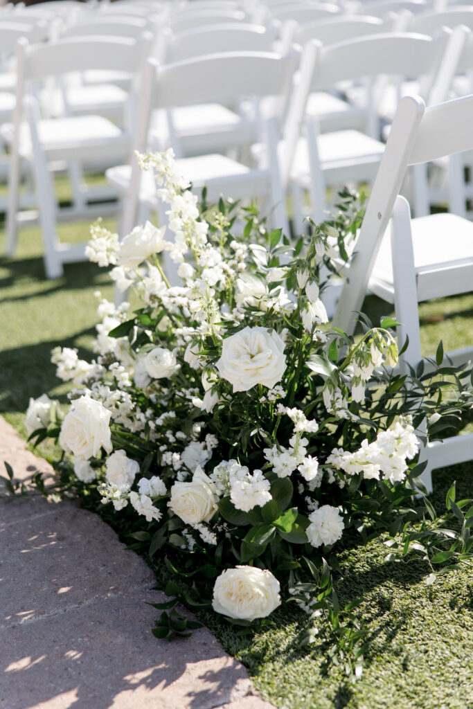 Back of wedding ceremony ground floral of white flowers and greenery.