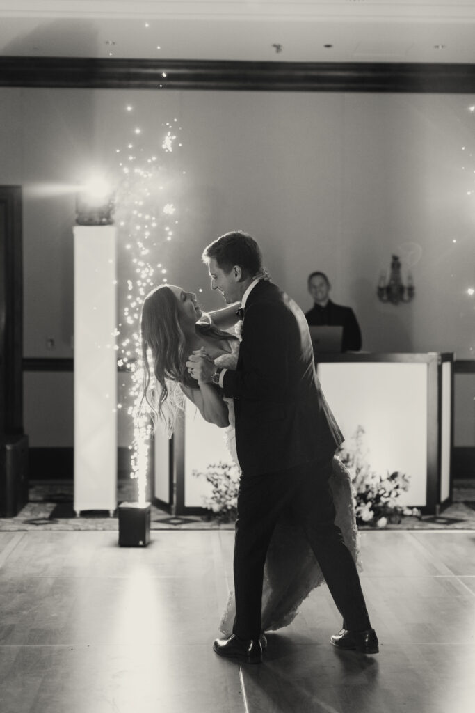 Groom dipping bride during dancing at wedding reception.