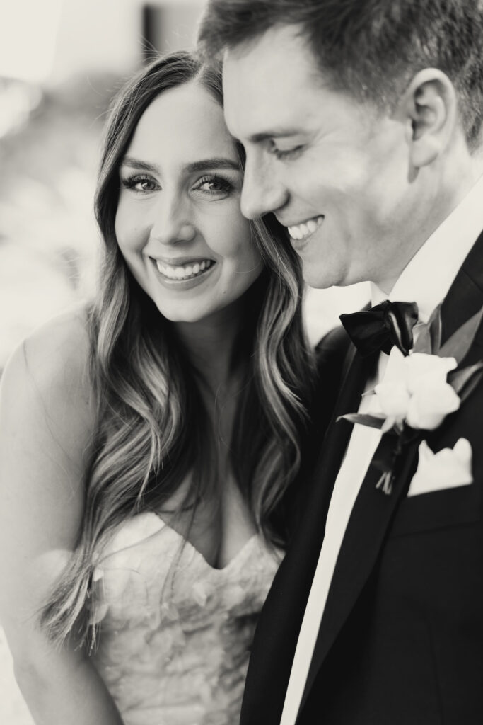 Bride and groom standing close, both smiling.