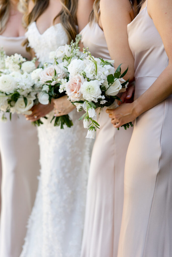 Bride and bridesmaids holding bouquets, standing in a line.