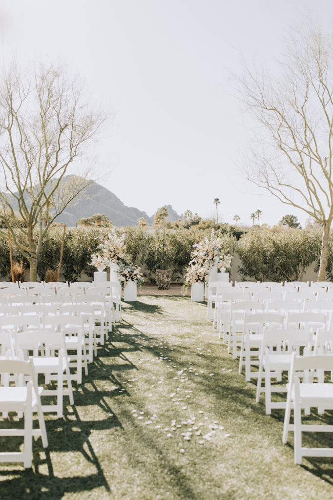 Andaz Resort outdoor wedding ceremony with white chairs, minimal aisle white rose petals and floral pillars in altar space.