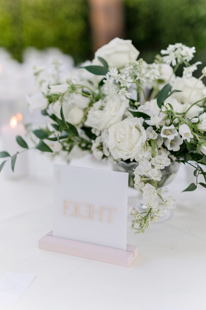 Reception table centerpiece with white flowers and greenery.