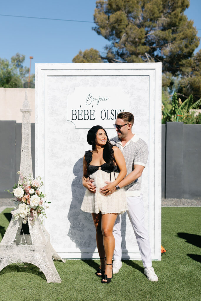 French themed wedding photo backdrop with mini Eiffel Tower, woman and man standing in front smiling.