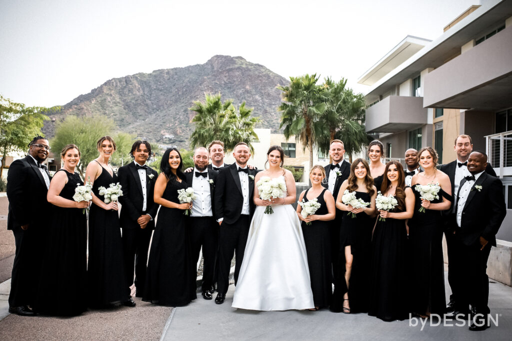 Bride and groom standing with wedding party at Mountain Shadows with desert mountains in the background.