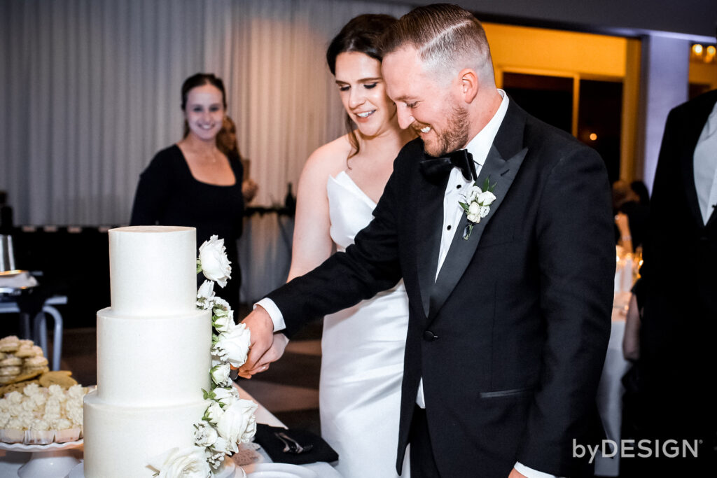 Bride and groom cutting white wedding cake.