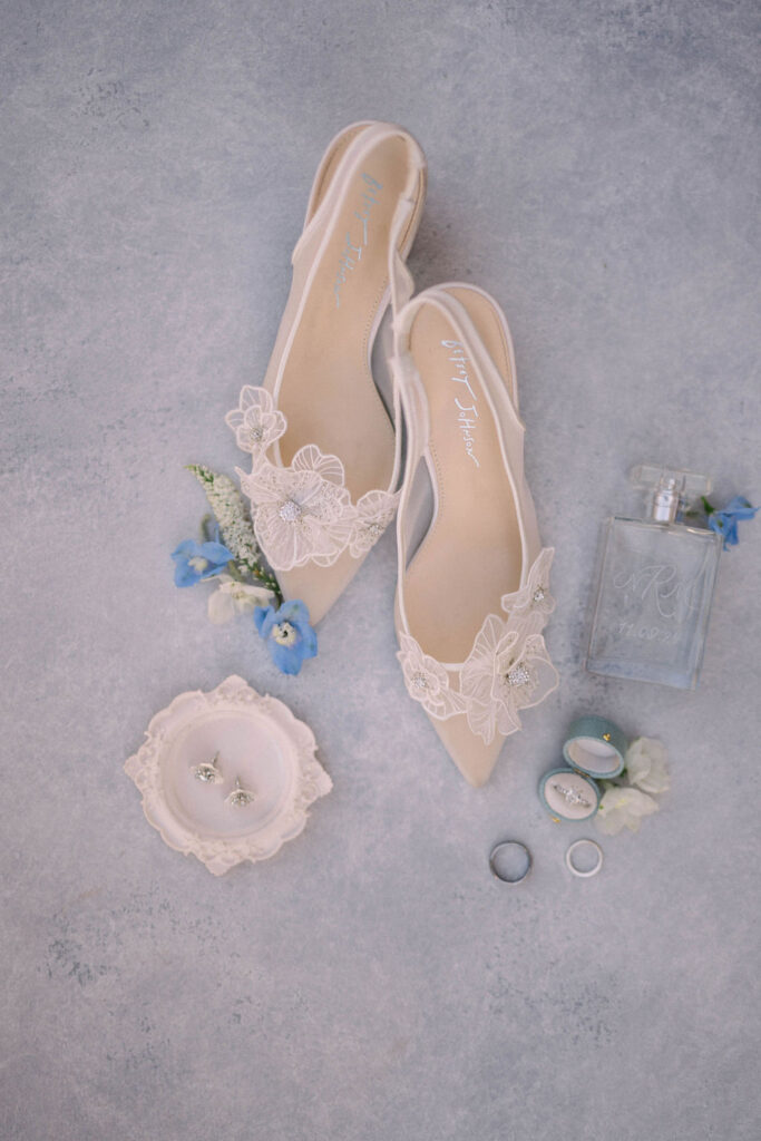 Bridal details including shoes, perfume, flowers, rings, earrings.