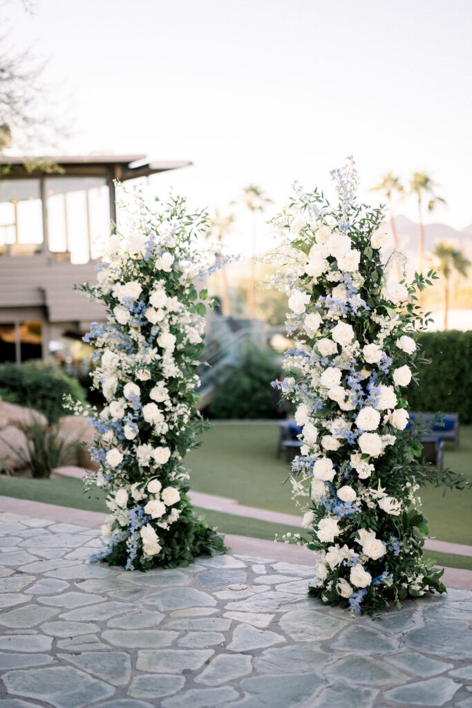 Custom floral pillars of white and blue flowers for wedding ceremony.