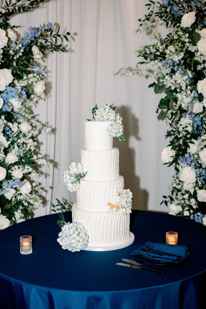 Four tiered white wedding cake with floral added.