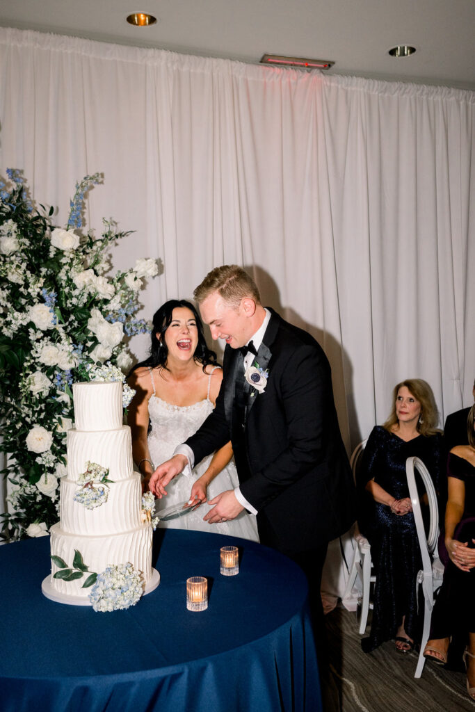 Bride and groom laughing during wedding cake cutting.