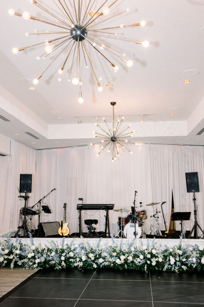 Sanctuary Resort indoor reception band stage with ground floral in front in blue and white colors.