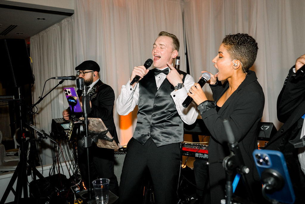 Groom singing with wedding band on stage.
