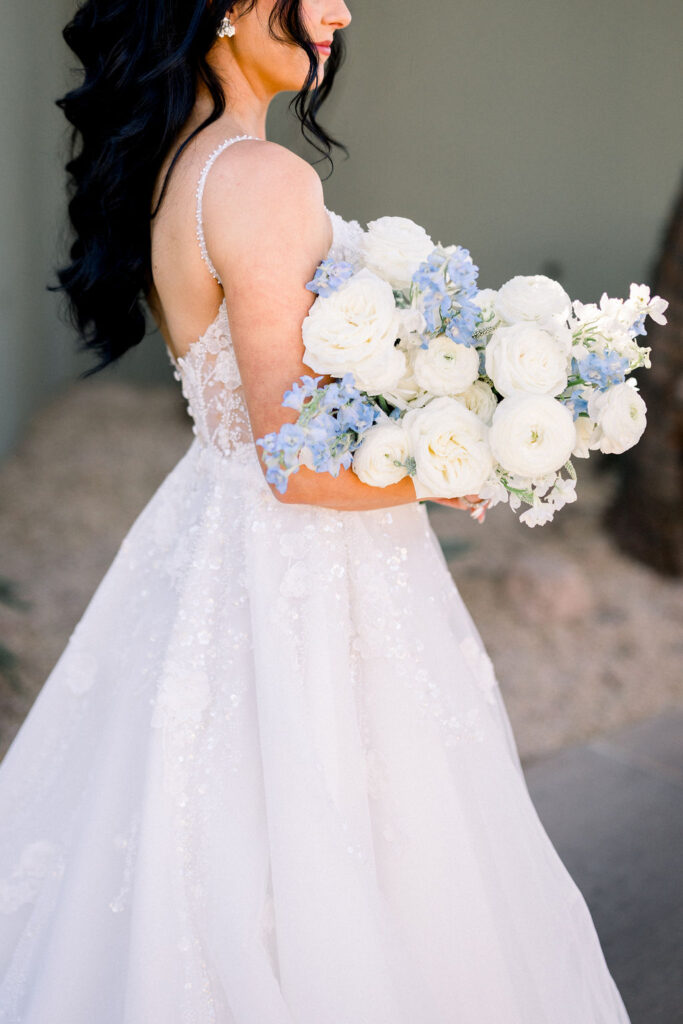 Lush bridal bouquet of white and blue flowers including roses.