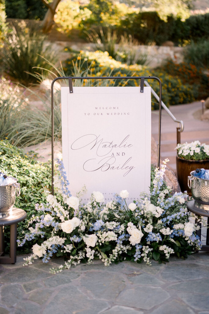 Wedding welcome sign with ground flowers around it.
