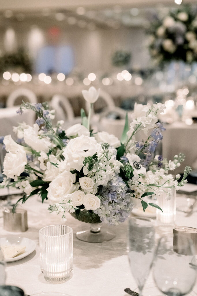 Low floral centerpiece of white and blue flowers for wedding reception.