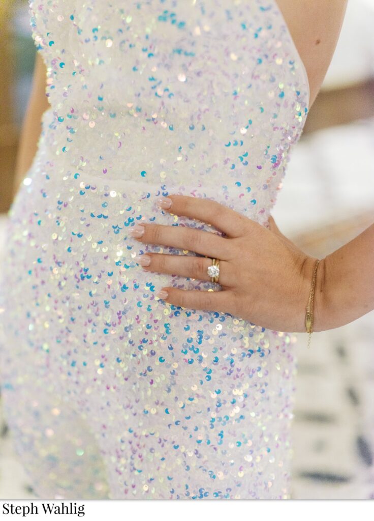 Details of bride's wedding ring she is wearing with hand on her hip.