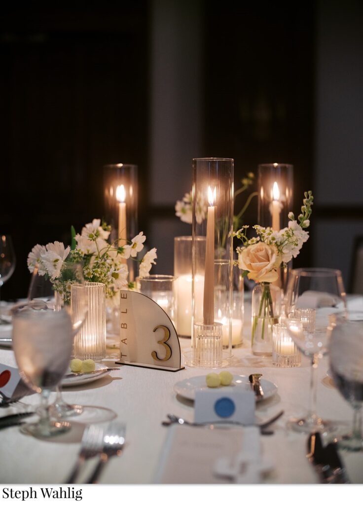 Bud vases and small floral arrangements with taper candles and votives centerpieces.