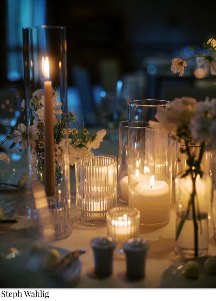 Candlelit wedding reception centerpiece with small floral arrangements.