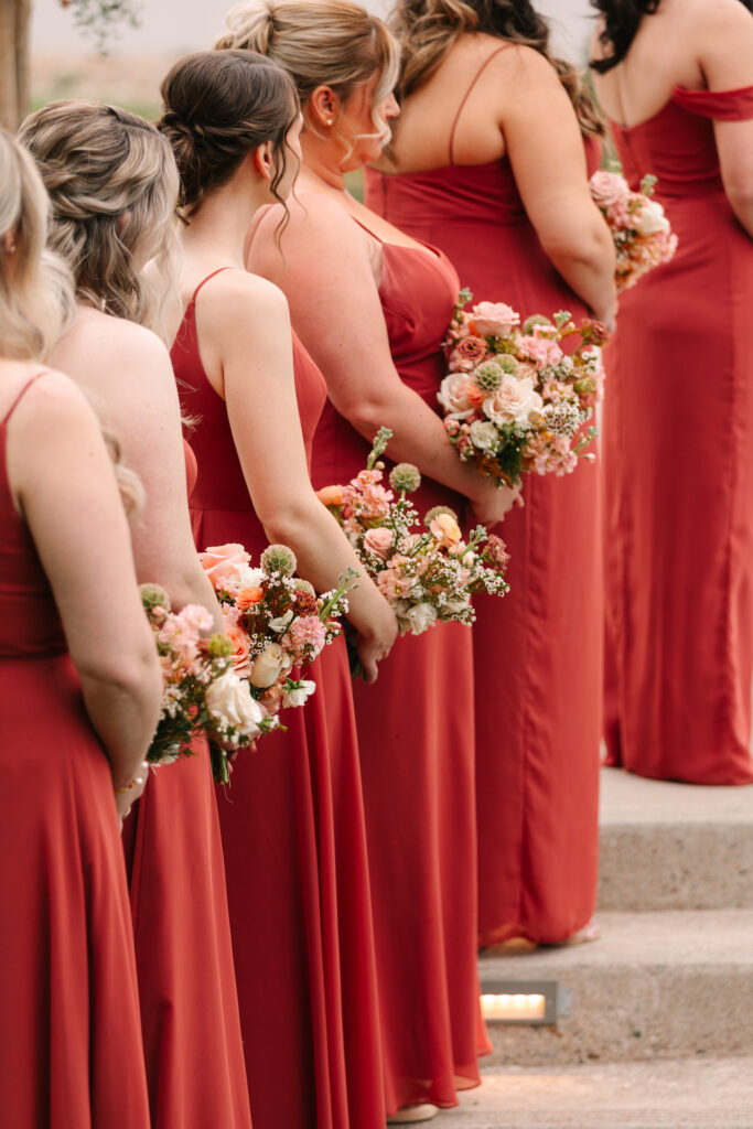 Bridesmaids standing during wedding ceremony in a line holding bouquets.